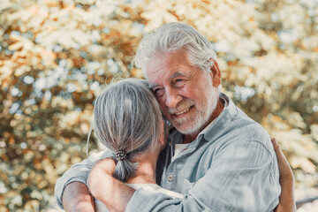 Beautiful cute couple of seniors hugged having fun and enjoying together outdoors in green park...