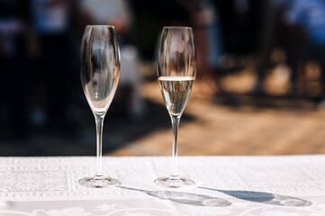 Filled and empty glasses stand on an outdoor table at a banquet party.