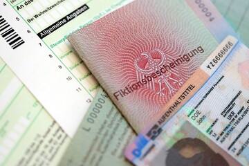 German Permanent resident card and temporary document lies on tax form. Aufenthaltstitel