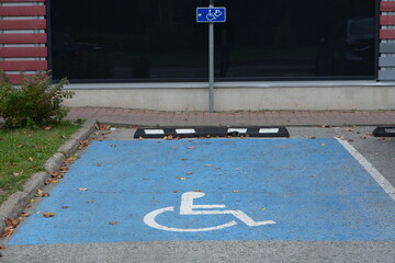 Top-Down View of a Dedicated Disabled Parking Space with White Wheelchair Symbol on Blue Asphalt and Curb Stop