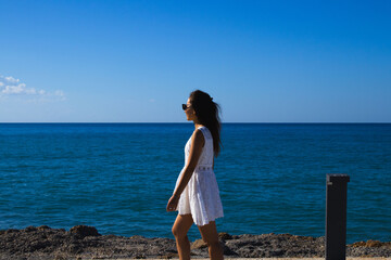 Woman in White Dress Walking Along Coastal Path Looking at the Sea