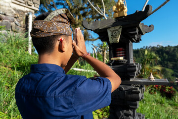Rear view of Balinese young man praying at Hindu shrine, Sidemen, Bali Indonesia. © cn0ra
