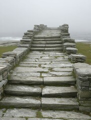 Fototapeta premium Old stone steps lead towards the foggy coast with ocean view, providing a sense of mystery and an uncertain destination outdoors.