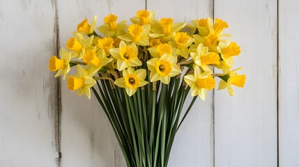 Cheerful yellow daffodil bouquet against white wooden background for spring theme