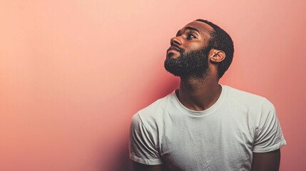 Obraz premium A man with a beard and mustache wearing a white t-shirt, standing against a pink background.