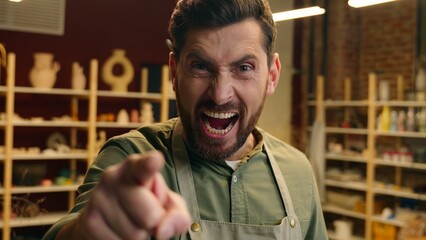 Angry mad furious Caucasian man male guy small business owner businessman potter seller salesman craftsman pointing index finger looking at camera gesture you rage anger screaming shout indoors store