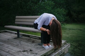 Woman sitting on a deck in Bear Creek Michigan near a creek with her hair hanging down 