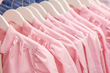 Row of Identical Pink Uniform Blouses on White Hangers. Retail or Salon Uniform