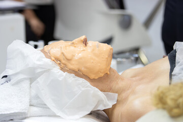 Woman Lying in Spa with Thick, Orange Alginate Mask on Her Face. Beauty Treatment