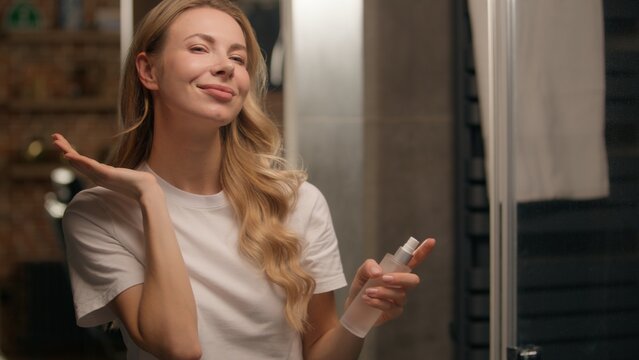 Fototapeta Happy Caucasian woman apply spray mist fixing makeup spraying micellar water toner young girl female model skincare product cosmetic beauty routine skin soothing facial moisturizing refreshing at bath