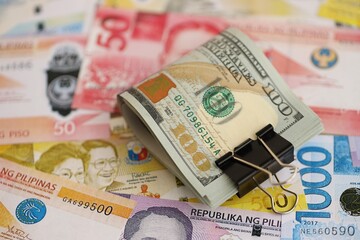 Philippines peso currency money bills and bunch of us dollar banknotes. The concept of economics and currency exchange