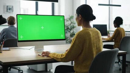 An inclusive office setting featuring diverse individuals working on computers with green screens, fostering collaboration and technology use - Powered by Adobe