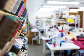 Spools of thread of various colors neatly arranged on wooden shelves, creating a visually appealing display for sewing and tailoring projects or facilities.