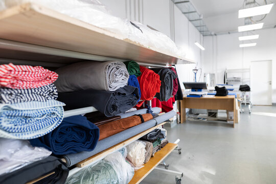 A mobile storage rack with rolls of colorful fabric in a modern garment factory. A concept of an organized workspace in the textile and fashion industry. - Powered by Adobe
