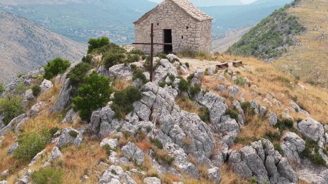 Ancient stone chapel on a coastal mountain ridge with panoramic sea view of the Dalmatian coast.