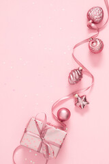 Vertical festive pink composition with gift box, ribbon, shiny baubles and stars on pastel background. Ideal for Christmas greeting cards, posters, web design and elegant holiday decor.