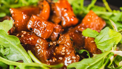 A vibrant bowl of sticky soy-honey glazed pork served over oriental rice with fresh rocket leaves. The peppery greens perfectly complement the sweet-savory pork and sesame topping.