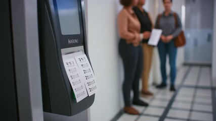 Biometric time clock in office hallway with employees nearby—capturing workplace attendance, access control, and professional routine.