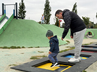 Father and son enjoying trampoline playtime at playground