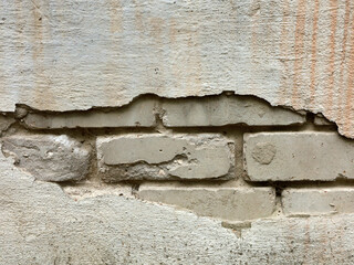 the facade of a white plastered house . the plaster crumbled.