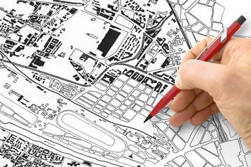Architect or Engineer drawing over an imaginary city map of territory with buildings, fields and roads