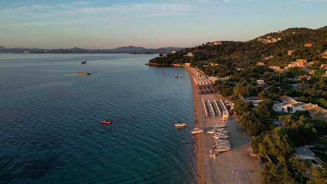 Scenic aerial view captures tranquil beach scene with gentle waves lapping against sandy shore, showcasing vibrant colors and serene atmosphere at sunset