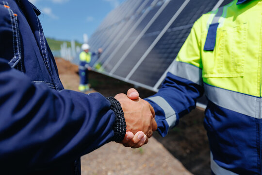 Business handshake between team workers in front of solar panels. Inspect installation photovoltaic cell and maintenance grid power station.