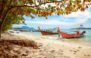 Longtail boats on the beach at Phuket, Thailand. View of tropical beach near Phuket in Thailand. Travel summer concept. Vacation holidays summer background. Sea wooden boat in Thailand.