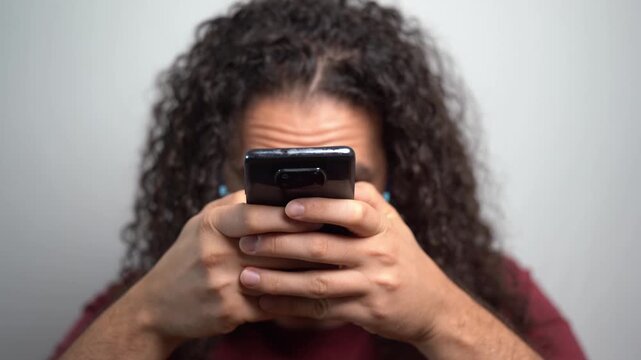 Young man with curly hair texting compulsively