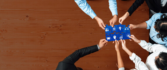 Diverse team members collaborate over a wooden table, connecting puzzle pieces that illustrate business strategies focused on growth and innovation. Amity