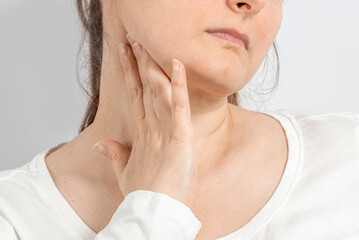 Woman over 35 holding her throat with her hand. Neck pain, lymph node