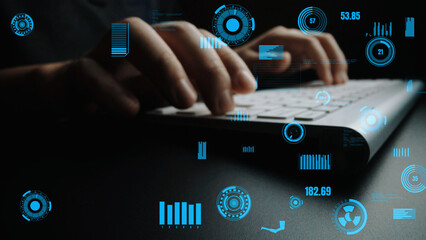 A close-up view of hands typing on a keyboard, surrounded by blue digital interface elements and graphs, illustrating data processing in a modern workspace. Xenic