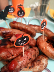 Halloween table setting with, sausages on a plate, festive decorations, and a carved pumpkin lantern glowing