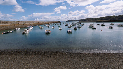 Schiffe in einem kleinen Hafen in der Bretagne in Frankreich mit einer Kaimauer als Begrenzung.
