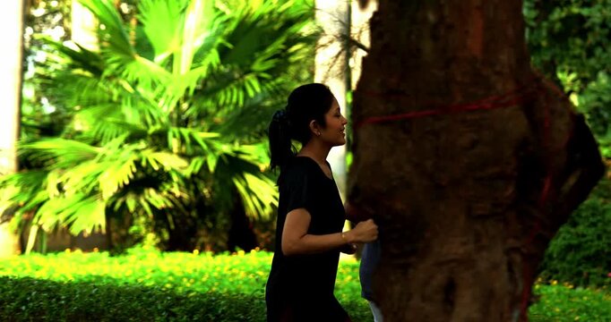 Indian young couple jogging in park together enjoying healthy morning routine and fitness oriented start of the day, spending quality time outdoors breathing fresh air surrounded in sunshine