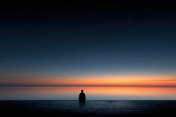 Fototapeta premium Person in silhouette meditating by the sea at sunset