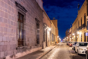 A quiet street at night with a row of buildings and parked cars on the side. Historic center of...