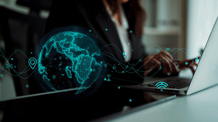 A professional woman types on a laptop with a glowing digital world map overlay, emphasizing technology and connectivity in a modern office setting. Xenic