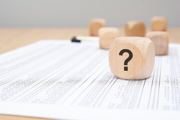 Wooden cube with question mark on financial document