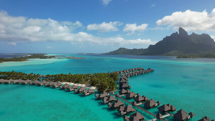 Luxury resort photos of French Polynesia tropical 
paradise islands with palm trees, thatched bungalows. Aerial perspective photography, coral reef, azure ocean, sky with clouds on horizon. 