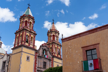 Obraz premium A historic building with two tall towers and a large window. The building is situated in a peaceful. Historic center of Queretaro, colonial architecture, decorations for the celebration of Mexico's In
