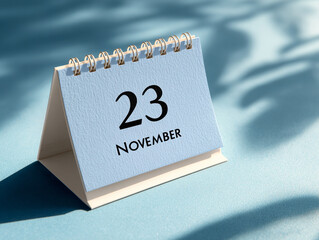 Calendar showing the date November 23 with a soft blue background and gentle shadows indicating time of year
