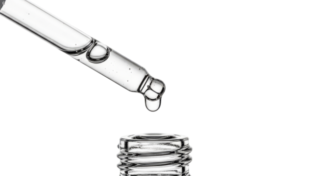 Clear dropper with a flowing drop a serum from it on transparent background. Skincare cosmetic product concept.