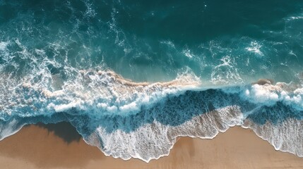 Stunning aerial view of vibrant turquoise ocean waves with white foam crashing onto a beautiful golden sandy beach shore, coastal seascape.