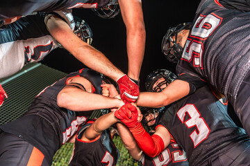 American football team huddling, joining fists for unity