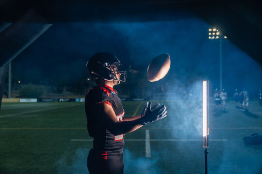 American football player catching ball during night game