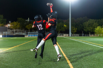 American football players jumping catching ball during game © unai