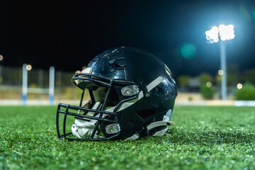 Fototapeta premium American football helmet lying on field at night