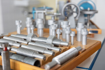 Reihen von metallischen Bauteilen sind gleichm&auml;&szlig;ig in einer Werkstatt oder Produktionsumgebung angeordnet. Das Motiv steht f&uuml;r industrielle Fertigung, Ordnung und pr&auml;zise Serienproduktion.