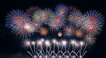 Fototapeta premium A breathtaking aerial fireworks show dazzling against the dark night sky, featuring numerous explosions of vibrant colors like red, blue, gold, and white